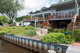 homewithseawall home with a swale, a berm and a seawall